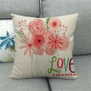 Close-up of linen pillow cover with floral pattern and LOVE text on a grey sofa
