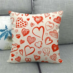 Detail view of linen pillowcase with red heart patterns and LOVE text on grey sofa