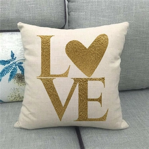 Detail of linen pillowcase with gold foil LOVE text and heart print on a sofa