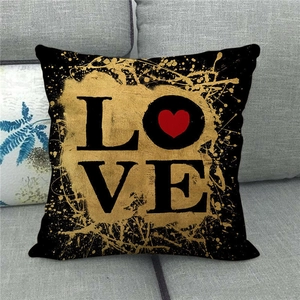 Detail of linen pillowcase with gold LOVE text and red heart on grey fabric sofa