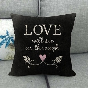 Detail of black linen pillow cover with white LOVE will see us through text on grey sofa
