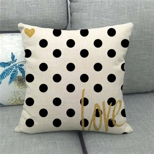 Detail of linen pillowcase with black polka dots, golden heart and artistic love lettering