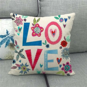 Close-up detail of linen cushion cover with colorful LOVE text and floral patterns