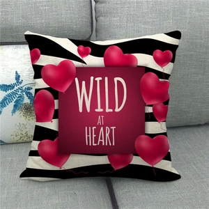 Linen cushion cover with zebra pattern, red hearts and Wild at Heart text on a sofa