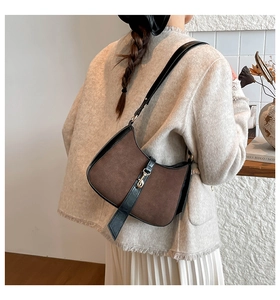 Detail of vintage brown suede hobo bag with gold piston closure worn over the shoulder