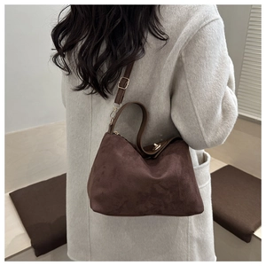 Detail of dark brown suede shoulder bag showing matte texture and adjustable gold buckle