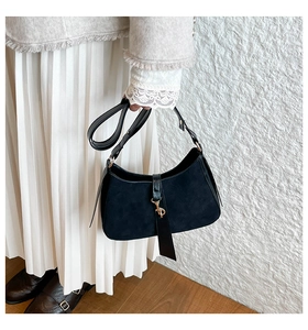 Detail of black crescent hobo bag featuring matte suede texture and gold metal buckle