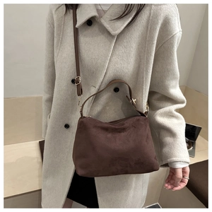Detail of dark brown matte suede shoulder bag with adjustable strap on wool coat