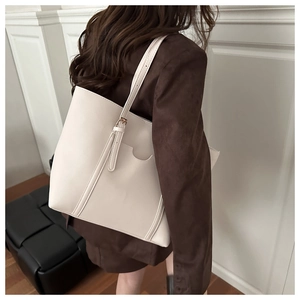 Large beige tote bag with adjustable strap shown on shoulder for daily commute style