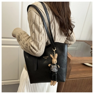 Detail of black tote bag with textured leather, lettering, and a cute bunny charm