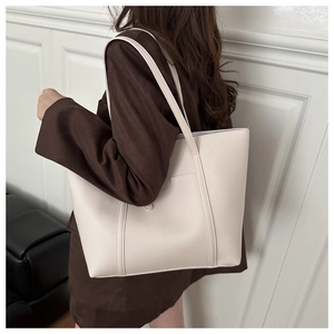 Détail d'un grand sac cabas en PU crème avec surpiqûres verticales et poche frontale