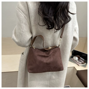 Deep brown matte suede Lindy-style shoulder bag shown on model in a minimalist setting