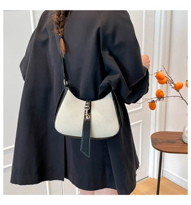 Detail of retro half-moon shoulder bag in beige canvas and black leather with silver buckle
