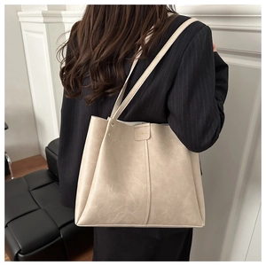 Detail of vintage beige leather tote bag with Fashion lettering on black blazer