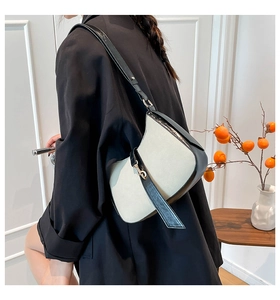 Close-up of contrast-colored shoulder bag featuring chic ribbons and golden metal buckle