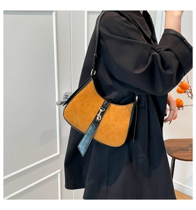 Detail of vintage suede shoulder bag showing brown and black patchwork with metal buckle