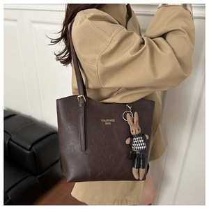 Detail of vintage brown leather tote bag with gold logo and cute rabbit charm