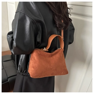 Detail of caramel suede handbag with golden buckle and leather handle on a model