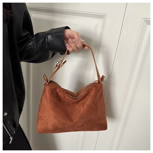 Detailed close-up of a brown suede hobo bag with a metallic twist lock and zipper