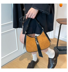 Detailed view of caramel frosted crescent bag featuring black leather trim and silver buckle