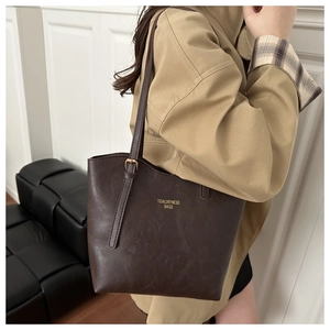 Close-up of dark brown retro leather tote bag with gold logo and adjustable shoulder strap