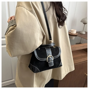 Detail of black suede crossbody bag featuring white contrast stitching and gold buckle