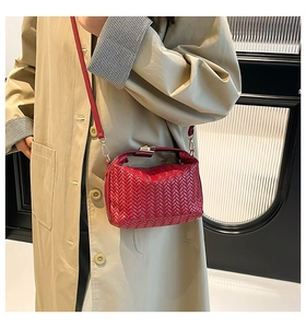 Detail of burgundy woven leather bag with gold clasp shown on trench coat model