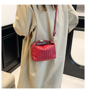 Detailed view of red woven leather shoulder bag with metallic clasp and strap