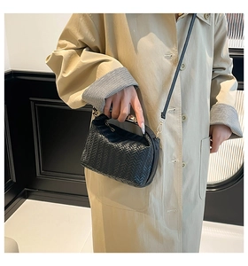Detail of black woven leather handbag with gold metal hardware and V-pattern texture