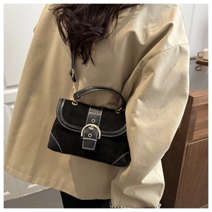 Black suede crossbody bag with white stitching and gold ring buckle shown on model