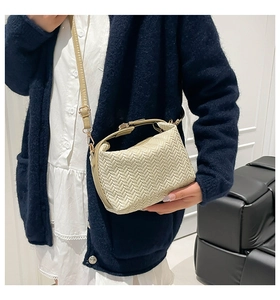 Close-up of beige woven texture crossbody bag with adjustable strap on a model
