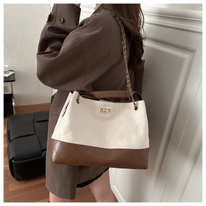 Side view of a quilted bicolor tote bag featuring a gold clasp and elegant chain strap