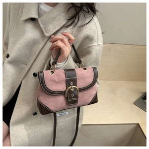 Detailed close-up of retro pink suede handbag with brown leather trim and golden buckle