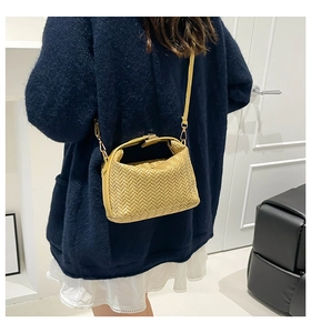 Detail of yellow woven PU leather crossbody bag with adjustable strap and gold hardware