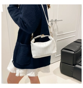 Detail of white woven texture shoulder bag with gold hardware on a blue cardigan