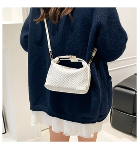 Detail shot of white woven texture leather handbag with adjustable crossbody strap