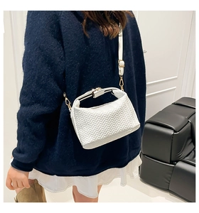 Detail of white woven dumpling bag with crossbody strap shown on a model