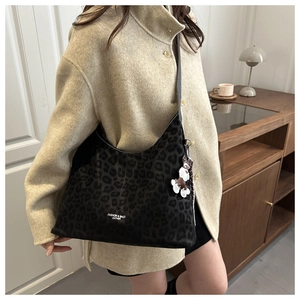 Detail of black leopard print shoulder bag with white flower charm and branded text