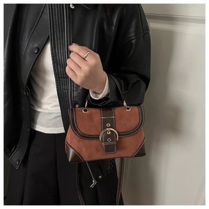 Detail of brown suede square bag featuring contrast stitching and golden buckle closure