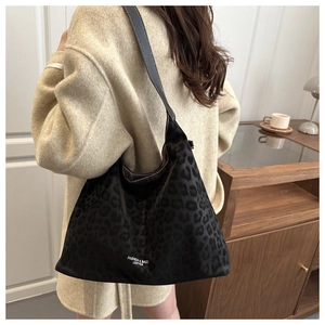 Detail of leopard print tote bag with leather straps on model in beige coat
