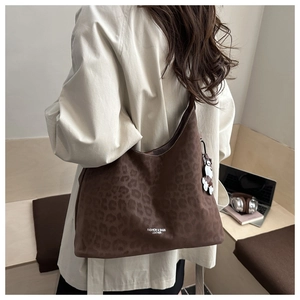Detail of leopard print faux suede crescent bag with charm in an urban lifestyle setting