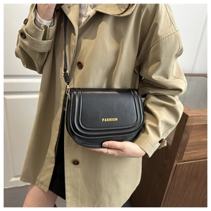 Detail view of black leather saddle bag with gold FASHION text and adjustable strap