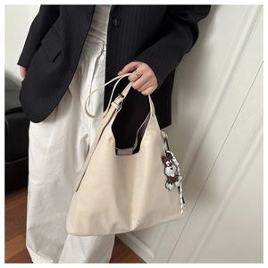 Close-up of cream leather hobo bag with adjustable strap and cute schnauzer charm