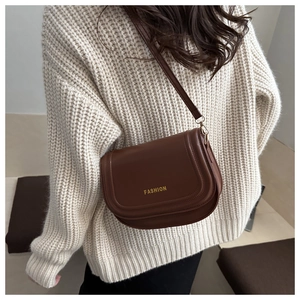 Close-up of a brown leather saddle bag featuring fine stitching and fashion lettering