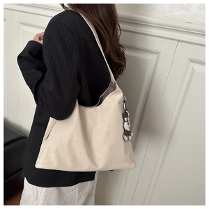 Detail of a large cream Hobo bag featuring a cute brown cartoon dog charm for commuting