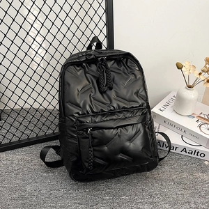 Minimalist black quilted backpack with large front pocket and woven zipper pulls