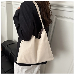 Model wearing a large cream faux suede tote bag, showcasing its size and drape on the shoulder