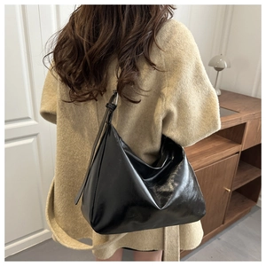 Détail de la boucle argentée ajustable et de la bandoulière en cuir verni noir brillant