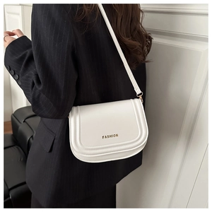 Close-up of white saddle shoulder bag with golden FASHION logo on black blazer model