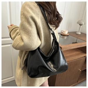 Vue de profil d'un grand sac hobo en cuir verni noir porté par un mannequin